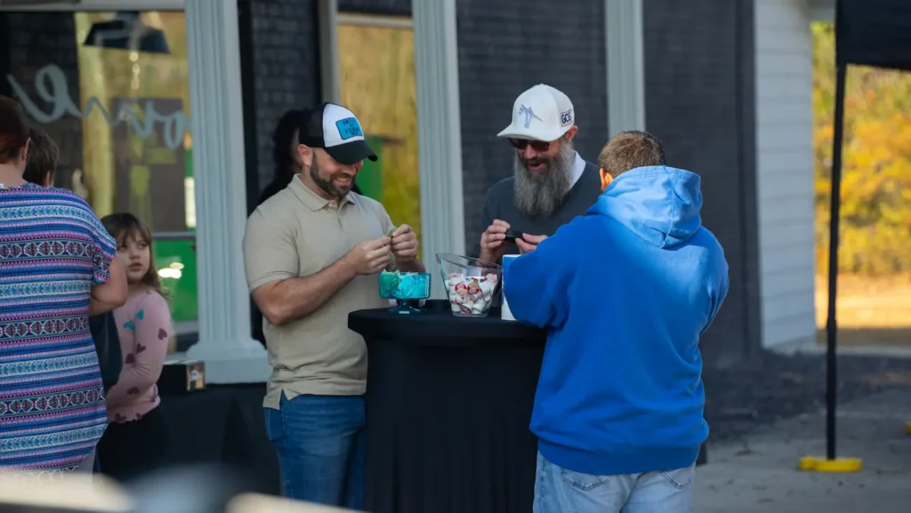 Group of men standing and chatting around coffee table.