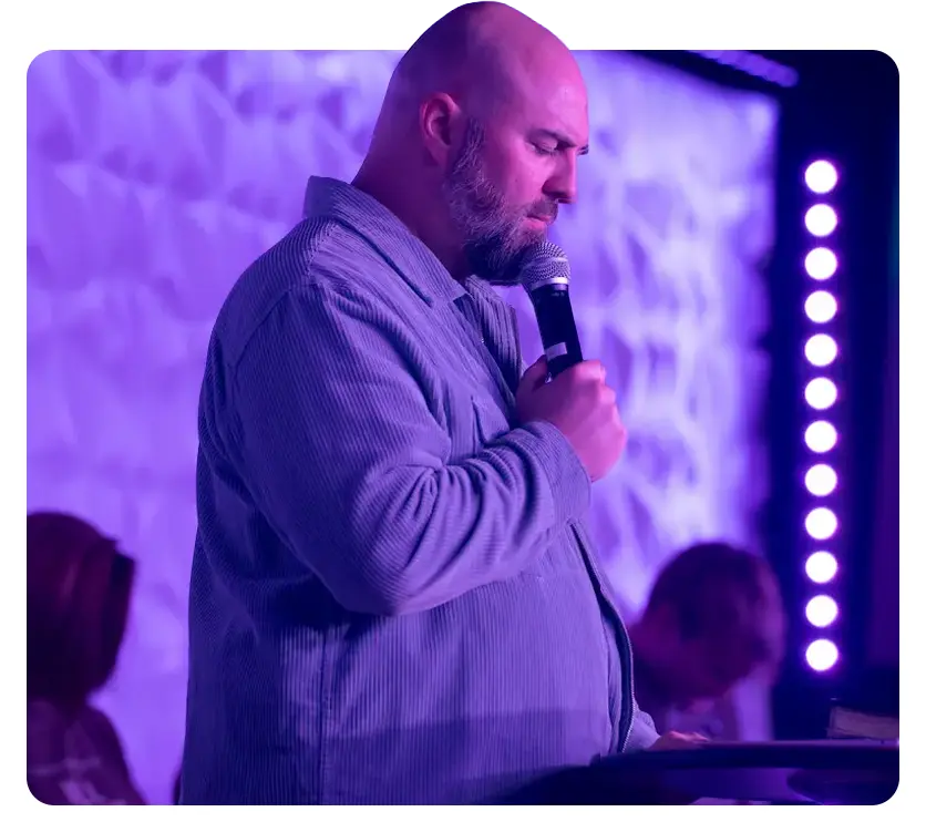 Derek Anglin preaching on stage.